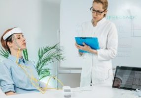 Biofeedback EEG or electroencephalograph training at a health center. Therapist monitoring brain waves using scalp sensors placed onto a client’s head